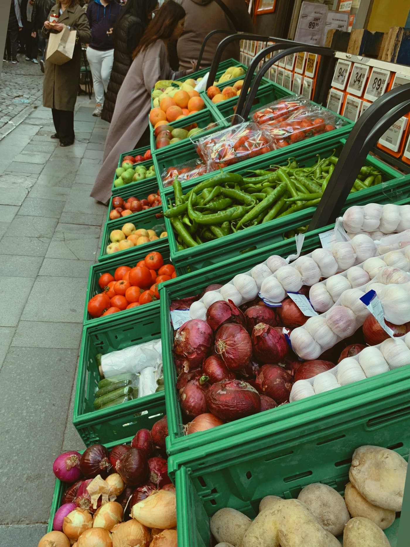 Produce in green crates on the sidewalk