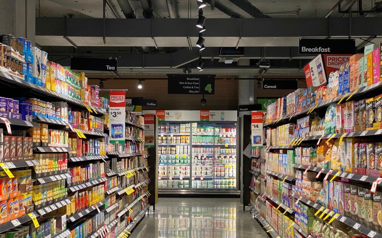 A brightly lit, fully stocked supermarket aisle