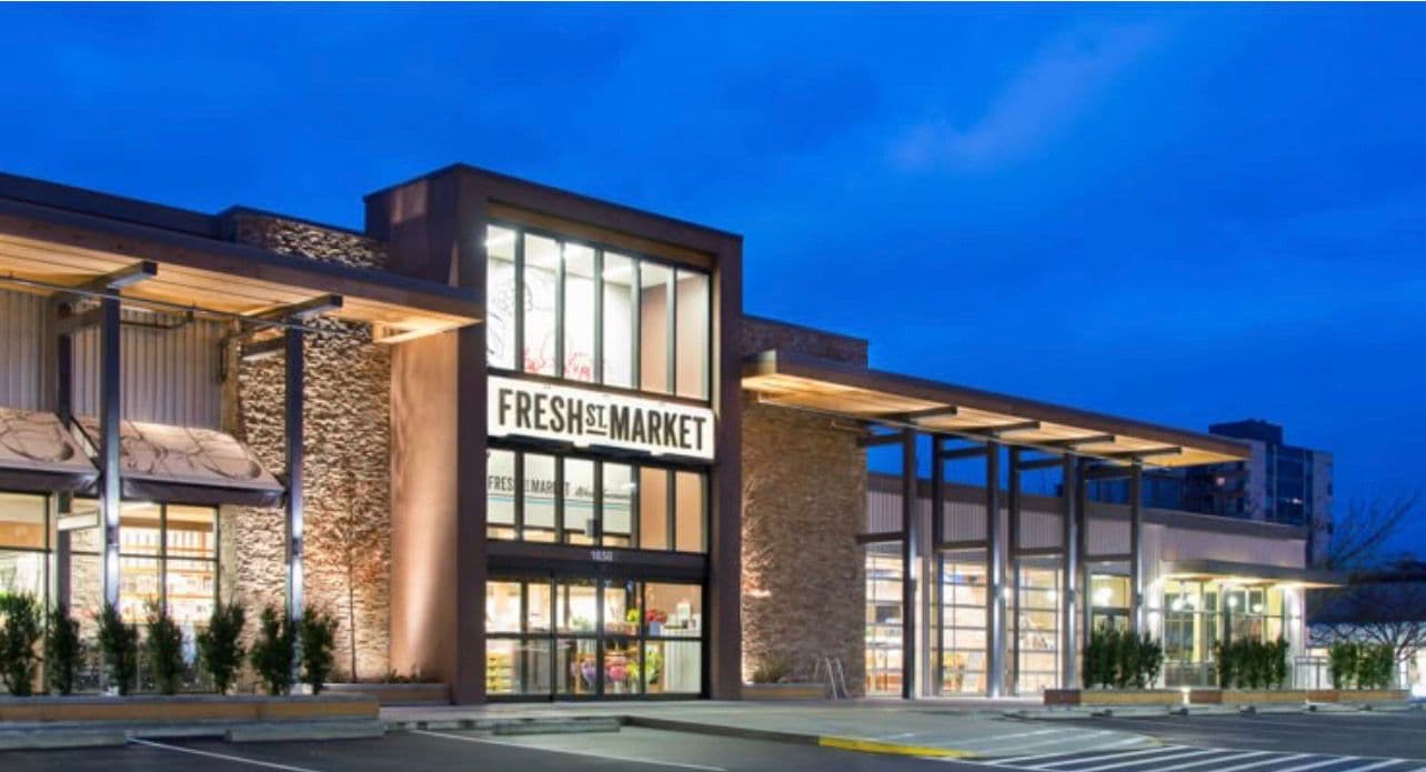 A modern supermarket storefront lit at dusk